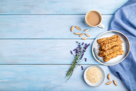 Crumble cookies with seasme and almonds on ceramic plate with cup of coffee and blue linen textile...
