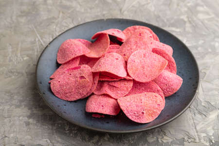 red potato chips with herbs and tomatoes on gray concrete background. Side view, close up.の写真素材