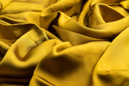 Fragment of yellow and green tissue. Side view, synthetic textile background and texture. wave concept, abstract.の写真素材