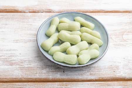 Jelly celery candies on white wooden background. side view, close up.