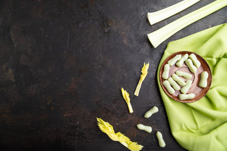 Jelly celery candies on black concrete background and green linen textile. copy space, top view,...