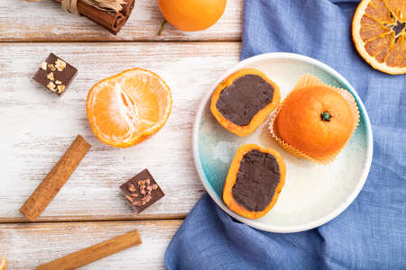 Truffle chocolate tangerine candies on a white wooden background and blue linen textile. top view, flat lay, close up.の写真素材