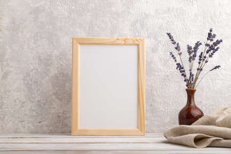 White wooden frame mockup with lavender in ceramic vase and linen textile on gray concrete background. Blank, vertical orientation, still life.の写真素材
