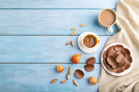 Chocolate chips with cup of coffee and caramel on a blue wooden background and linen textile. top view, flat lay, copy space.の写真素材