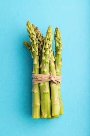 Bunch of fresh green asparagus on blue pastel background. Top view, flat lay, close up. harvest, healthy, vegan food, concept, minimalism.の写真素材