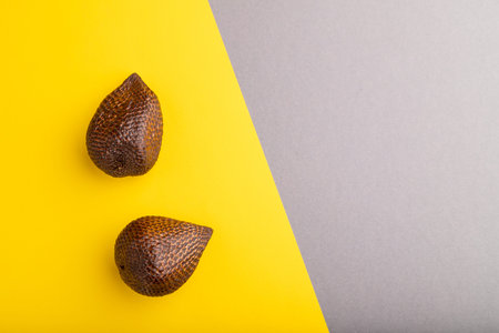 Salak or snake fruit on gray and yellow pastel background. Top view, flat lay, copy space. Tropical,...