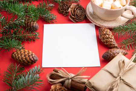 Christmas or New Year frame composition, template. Decorations, box, cinnamon, cones, fir and spruce branches, cup of coffee, on a red paper background. Side view, copy space.の写真素材