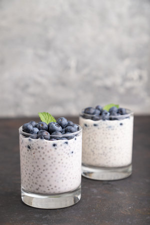 Yogurt with blueberry and chia in glass on black concrete background. Side view, close up, copy space.の写真素材