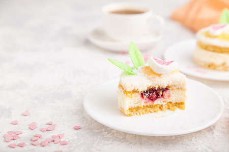 Decorated cake with milk and coconut cream with cup of coffee on a gray concrete background and orange textile. Side view, copy space.の写真素材