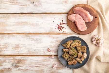 Stewed turkey fillet with garlic on white wooden background and linen textile. Top view, flat lay, copy space.の写真素材
