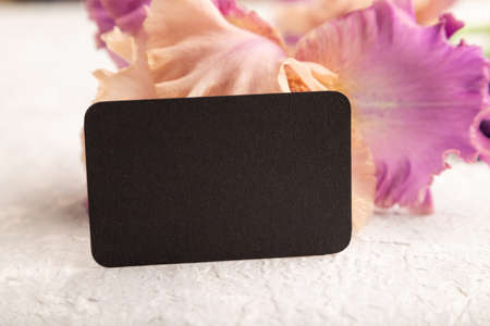 Black business card with iris purple flowers on white concrete background. side view, copy space, mockup, template, spring, summer minimalism concept.の写真素材