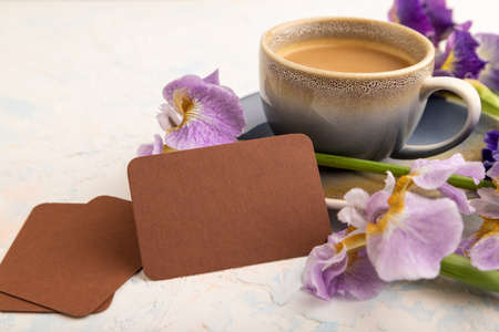 Brown business card with cup of cioffee and iris flowers on white concrete background. side view, copy space, still life. Breakfast, morning, spring concept.の写真素材