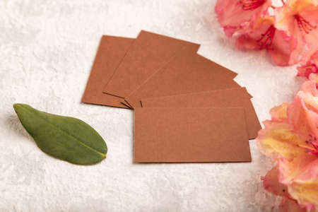 Brown business card with pink azalea flowers on gray concrete background. side view, copy space, mockup, template, spring, summer minimalism concept.の写真素材