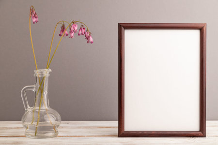 Wooden frame with pink dicentra, broken heart in glass on gray pastel background. side view, copy space, mockup, template, spring, summer minimalism concept.の写真素材