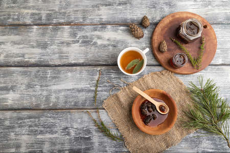 Pine cone jam with herbal tea on gray wooden background and linen textile. Top view, flat lay, copy space.の写真素材