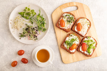 Red beet bread sandwiches with cream cheese, tomatoes and microgreen on gray concrete background....