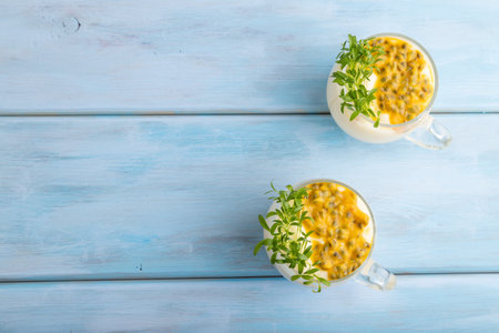 Mango yogurt with passionfruit and cilantro microgreen in glass on blue wooden background. Top view, flat lay, copy space.の写真素材