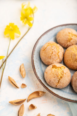 Almond cookies and a cup of coffee on a white concrete background and blue linen textile. Side view,...