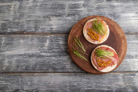 Puffed rice cake sandwiches with jerky salted meat, carrot microgreen on gray wooden background. top view, flat lay, copy space.の写真素材