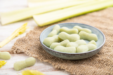Jelly celery candies on white wooden background and linen textile. close up, side view, selective...