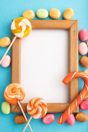 Composition with candies and wooden frame on blue pastel background. copy space, top view, flat lay,...