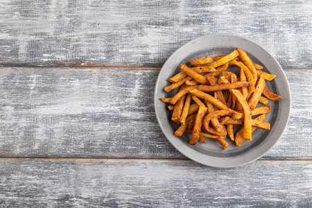 Heap of fried potato on a gray plate on a gray wooden background. Top view, flat lay, close up, copy...