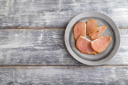 salted meat on a wooden plate on a gray wooden background. Top view, flat lay, close up, copy space.の写真素材