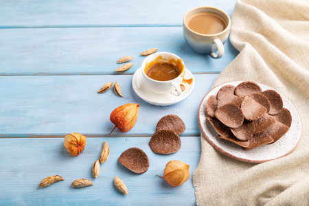 Chocolate chips with cup of coffee and caramel on a blue wooden background and linen textile. side view, copy space.の写真素材