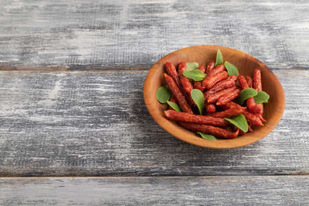 Small smoked sausage with borage microgreen, salt and pepper on gray wooden background. Side view, copy space.の写真素材