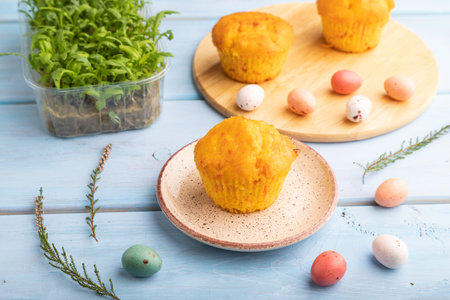 Homemade cakes with chocolate eggs and chrysanthemum microgreen on a blue wooden background. side...