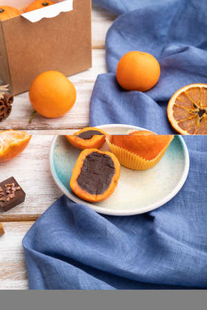 Truffle chocolate tangerine candies on a white wooden background and blue linen textile. side view,...