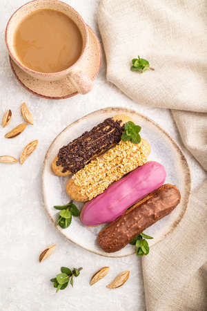 Set of eclair, traditional french dessert and cup of coffee on gray concrete background and linen textile. top view, flat lay, close up, still life. Breakfast, morning, concept.の写真素材