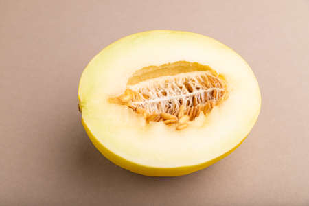 Sliced ripe yellow melon on brown pastel background. side view, close up. harvest, women health, vegan food, concept, minimalism.の写真素材