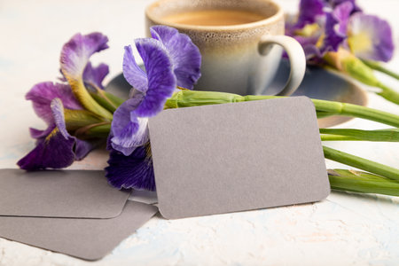 Gray business card with cup of cioffee and iris flowers on white concrete background. side view, copy space, still life. Breakfast, morning, spring concept.の写真素材