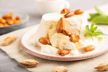 Ricotta cheese with honey and almonds on gray concrete background and linen textile. side view, close up, selective focus.の写真素材