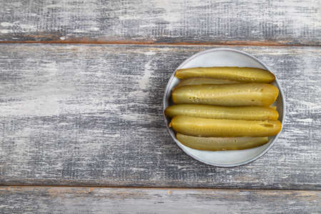 marinated cucumber on a blue ceramic plate on a gray wooden background. Top view, flat lay, close up, copy space.の写真素材