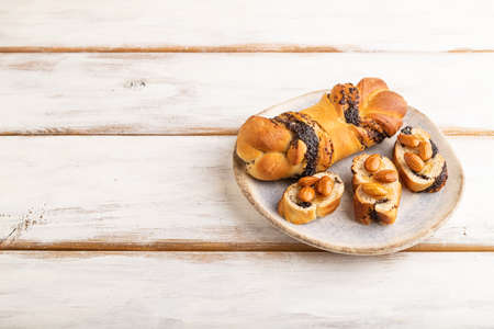 Homemade sweet bun with honey almonds on a white wooden background. side view, copy space.の写真素材