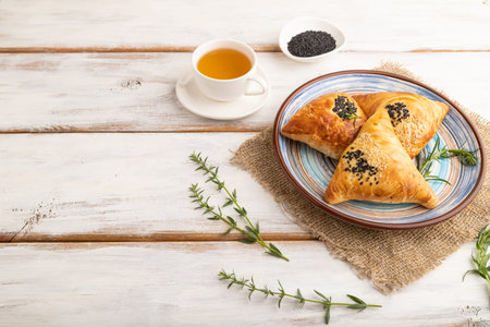 Homemade asian pastry samosa, cup of green tea on white wooden background and linen textile. side view, copy space.の写真素材