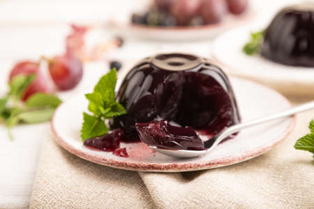 Black currant and grapes jelly on white wooden background and linen textile. side view, close up, selective focus.の写真素材