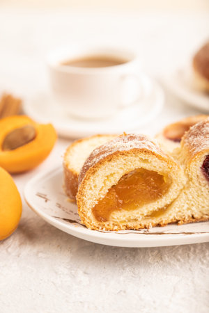 Homemade sweet bun with apricot jam and cup of coffee on gray concrete background. side view, close up, selective focus.の写真素材
