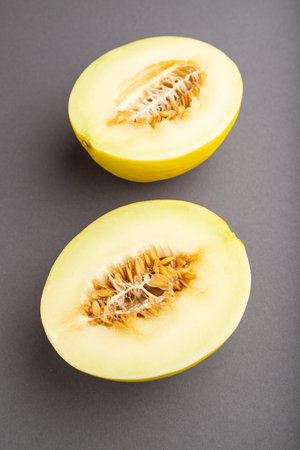 Sliced ripe yellow melon on gray pastel background. side view, close up. harvest, women health, vegan food, concept, minimalism.の写真素材