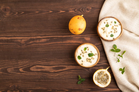 Yoghurt with granadilla and mint in wooden bowl on brown wooden background and linen textile. top...
