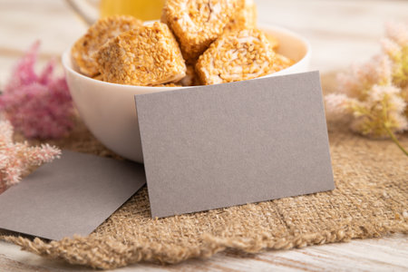Gray business card with traditional Turkish delight (rahat lokum) in white ceramic bowl on a white...