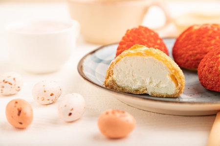 Traditional french custard dessert shu cake and cup of green tea on white wooden background and...