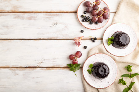 Black currant and grapes jelly on white wooden background and linen textile. top view, flat lay,...