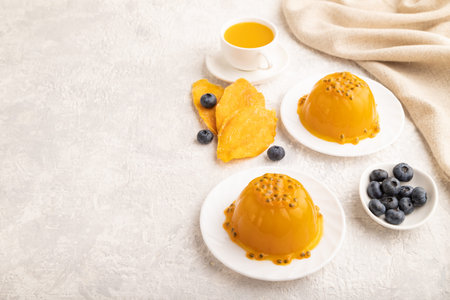 Mango and passion fruit jelly with blueberry on gray concrete background and linen textile. side view, copy space.の写真素材