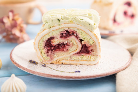 Roll biscuit cake with cream cheese and jam, cup of coffee on blue wooden background and linen textile. side view, close up, selective focusの写真素材