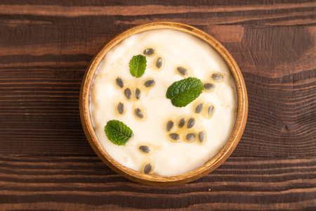Yoghurt with granadilla and mint in wooden bowl on brown wooden background. top view, flat lay, close up.の写真素材