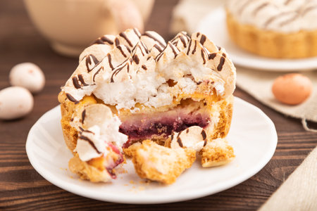 Tartlets with meringue cream and cup of coffee on brown wooden background and linen textile. side...