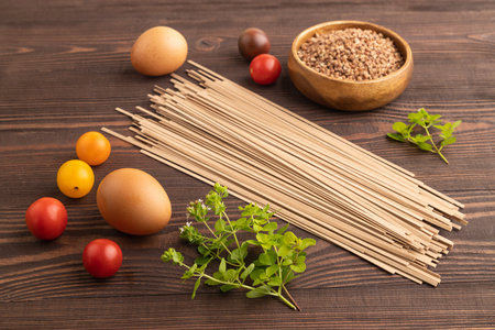 Japanese buckwheat soba noodles with tomato, eggs, spices, herbs on brown wooden background. Side...